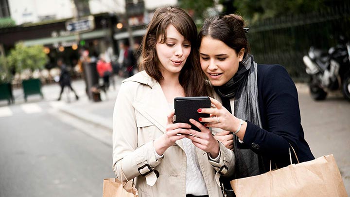 Two women looking at one mobile device